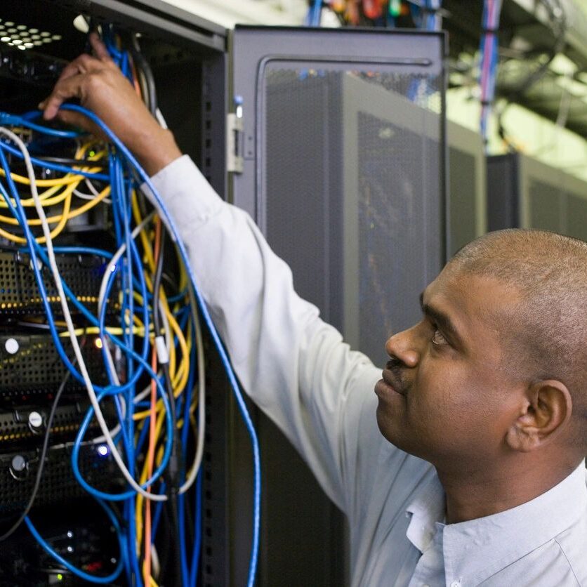 Technician managing cables in a server room.