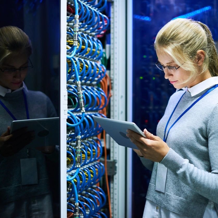 Woman working in server room with tablet.
